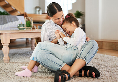 Buy stock photo Shot of a mother tickling her little daughter while relaxing together at home