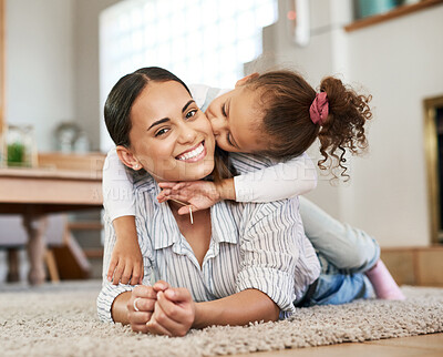 Buy stock photo Shot of a little girl giving her mother a kiss on the cheek while relaxing together at home
