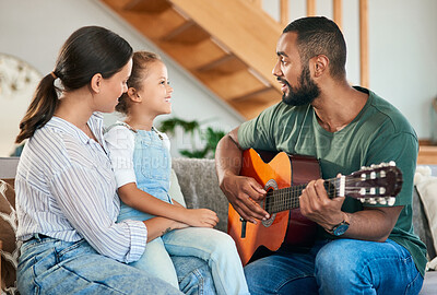 Buy stock photo Shot of a father playing an acoustic guitar for his wife and little daughter at home