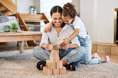 Buy stock photo Shot of a mother and her daughter playing with wooden blocks together at home