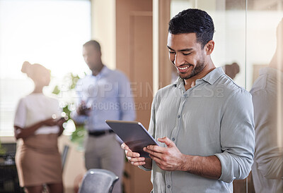 Buy stock photo Shot of a young businessman using his digital tablet at work