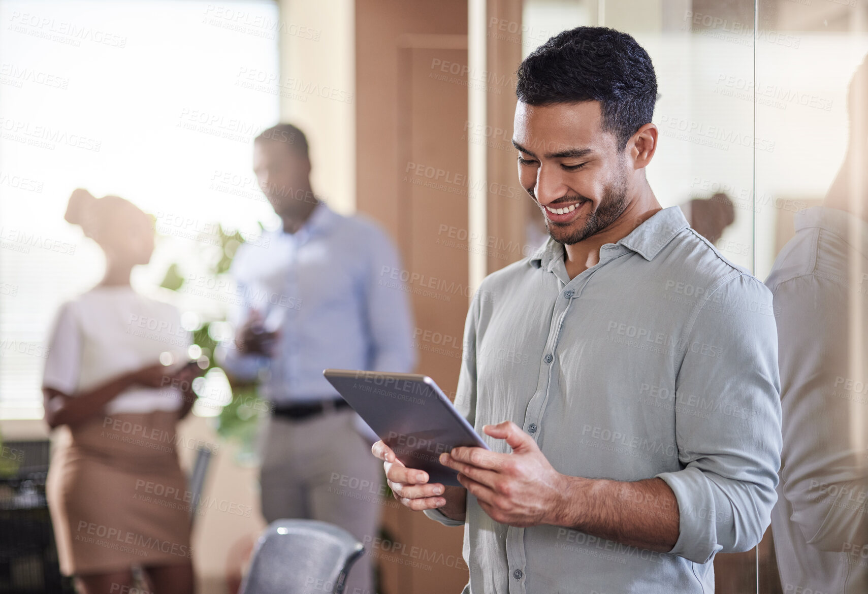 Buy stock photo Shot of a young businessman using his digital tablet at work