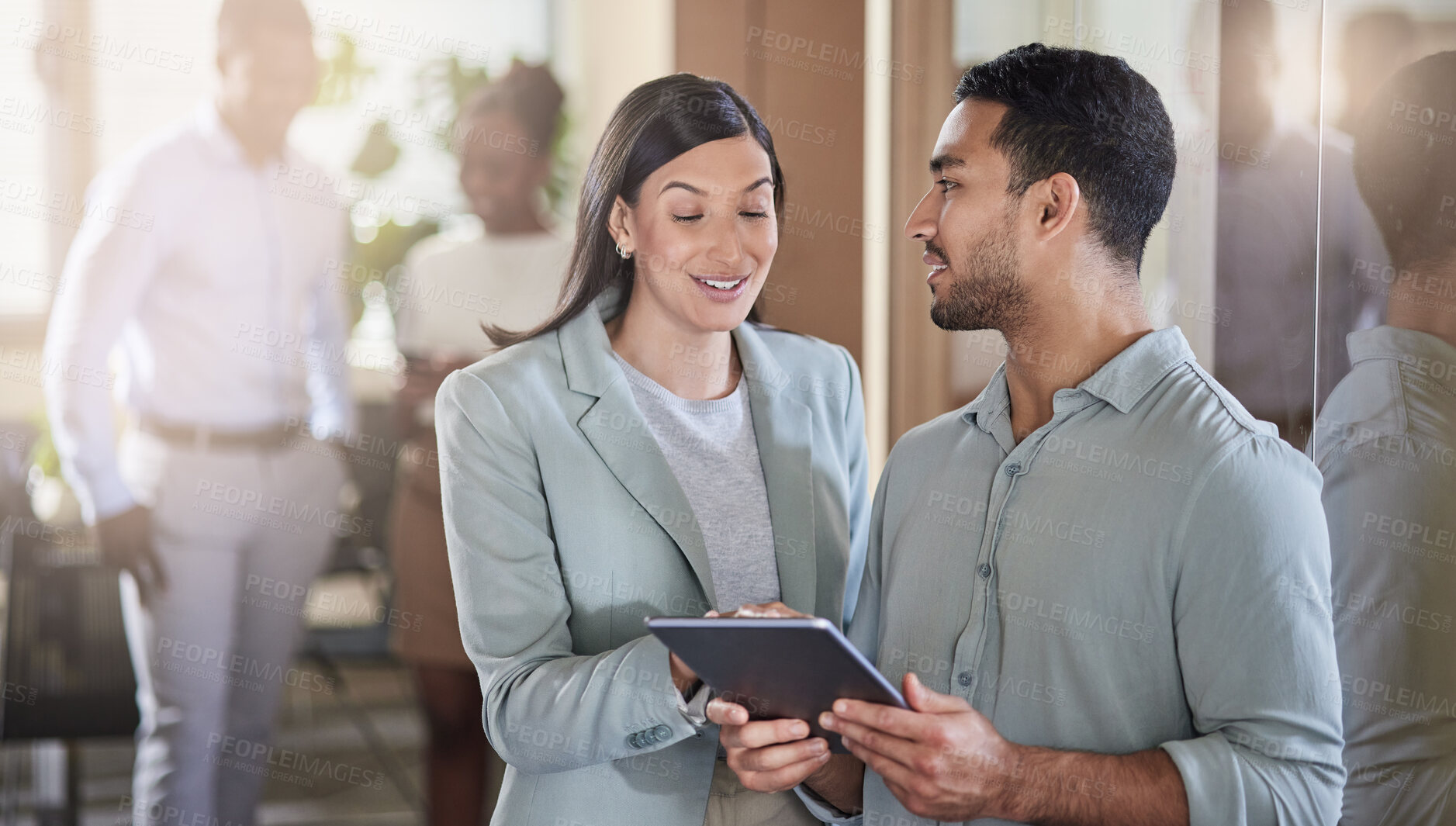 Buy stock photo Shot of two coworkers talking while using a digital tablet