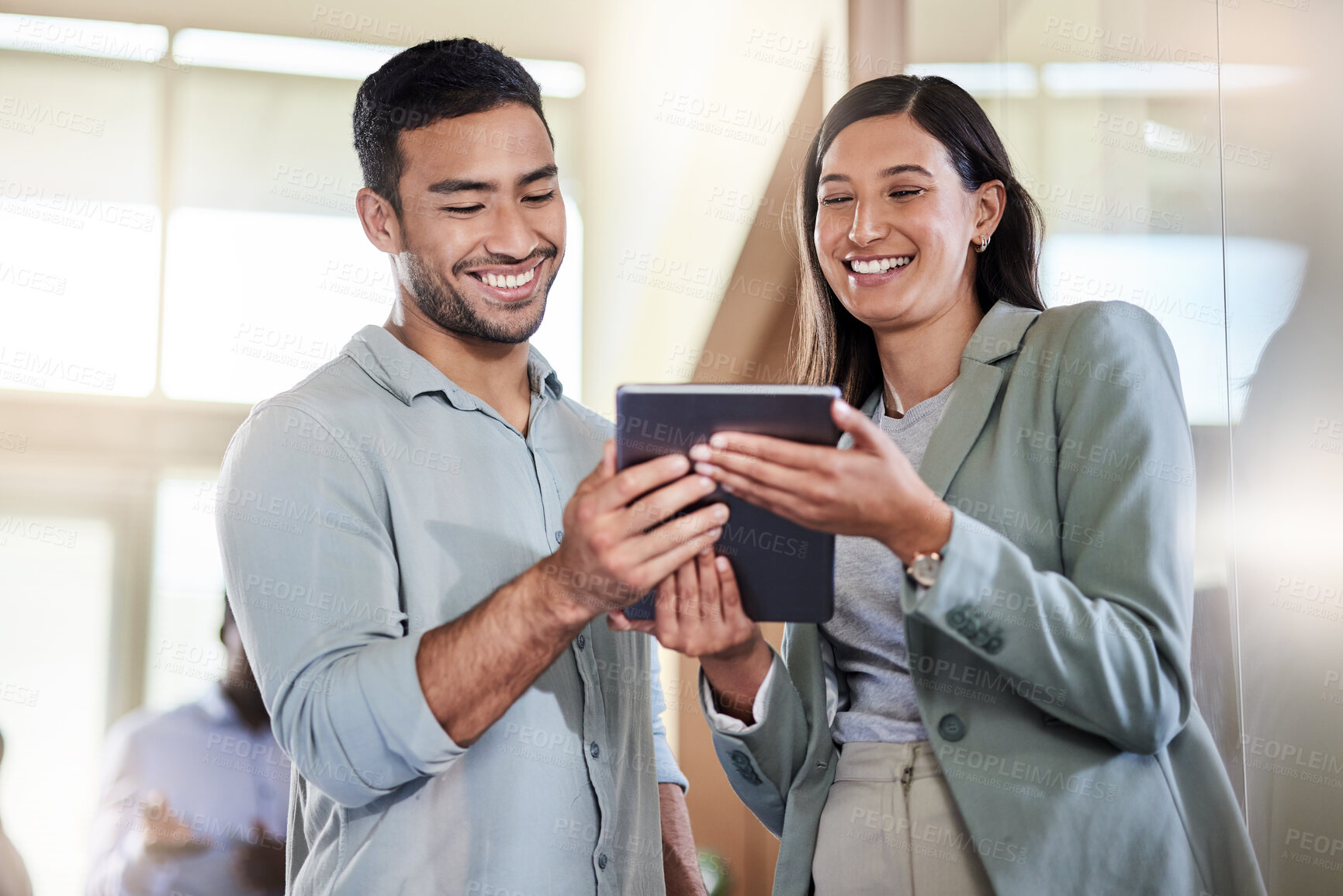 Buy stock photo Shot of two coworkers talking while using a digital tablet