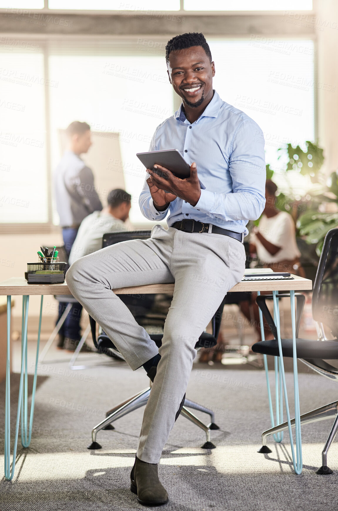 Buy stock photo Shot of a young businessman using his digital tablet at work