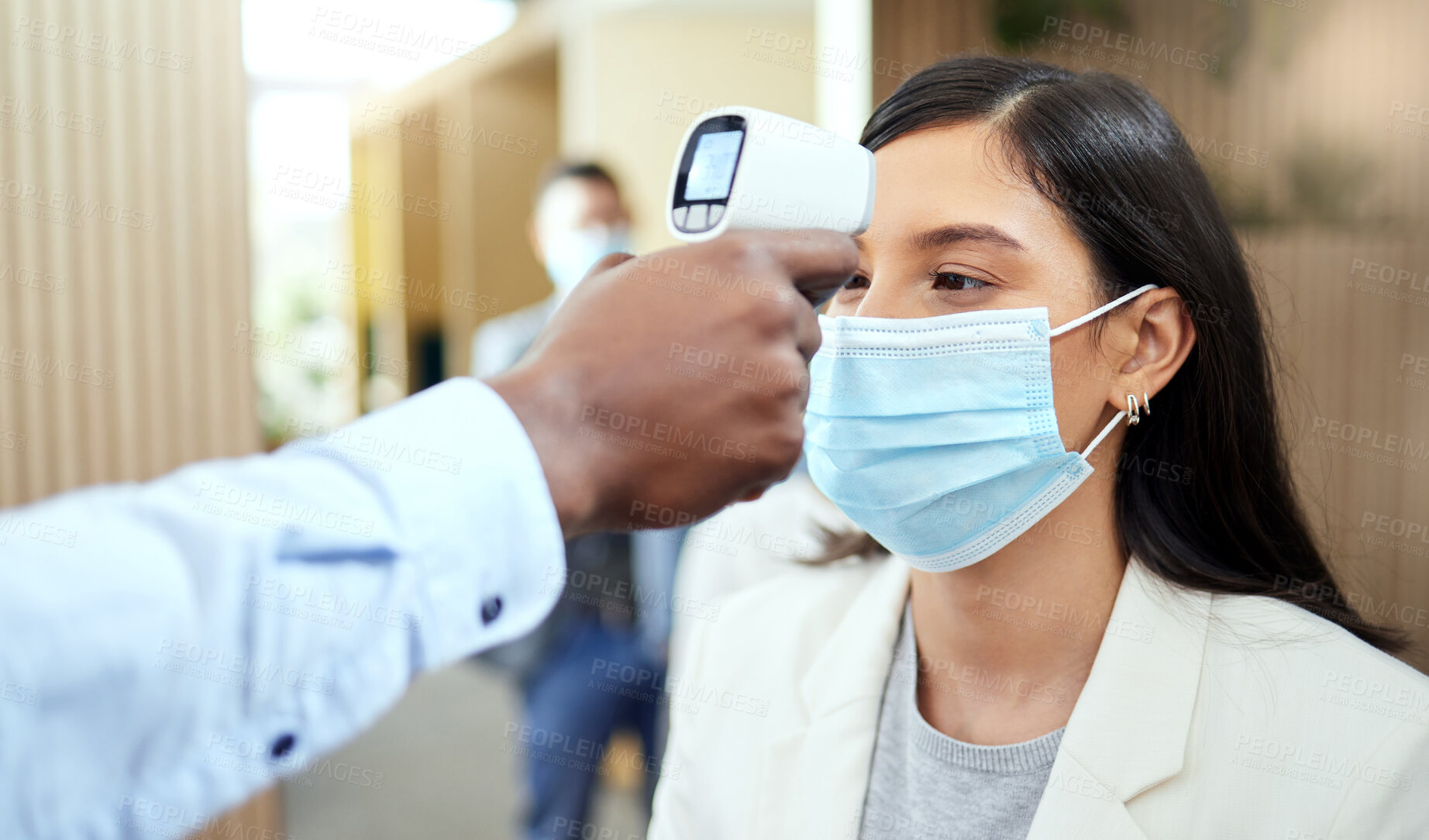 Buy stock photo Cropped shot of an attractive young businesswoman wearing a mask and having her temperature taken while standing at the head of a queue in her office