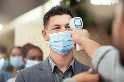 Buy stock photo Cropped shot of a handsome mature businessman wearing a mask and having his temperature taken while standing at the head of a queue in his office