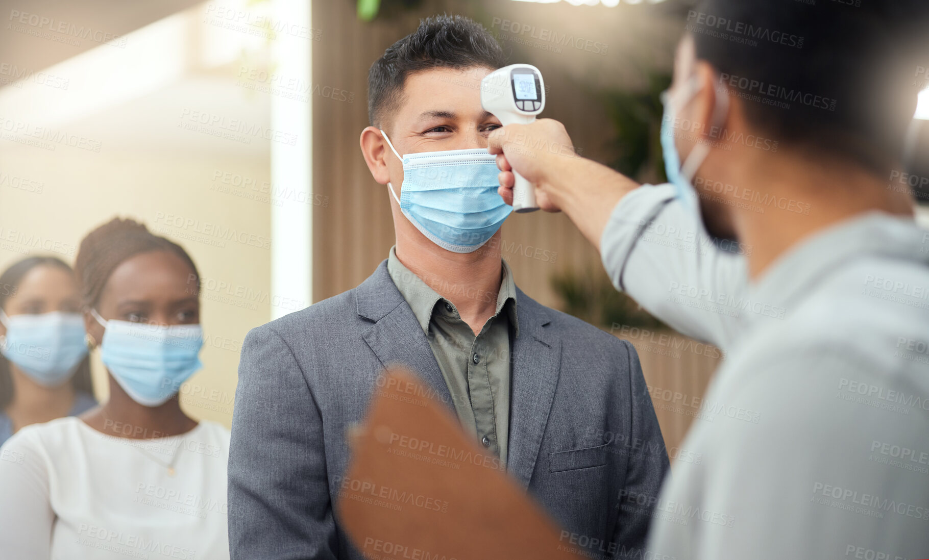 Buy stock photo Cropped shot of a handsome mature businessman wearing a mask and having his temperature taken while standing at the head of a queue in his office