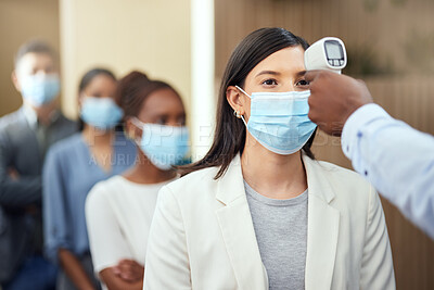 Buy stock photo Cropped shot of an attractive young businesswoman wearing a mask and having her temperature taken while standing at the head of a queue in her office