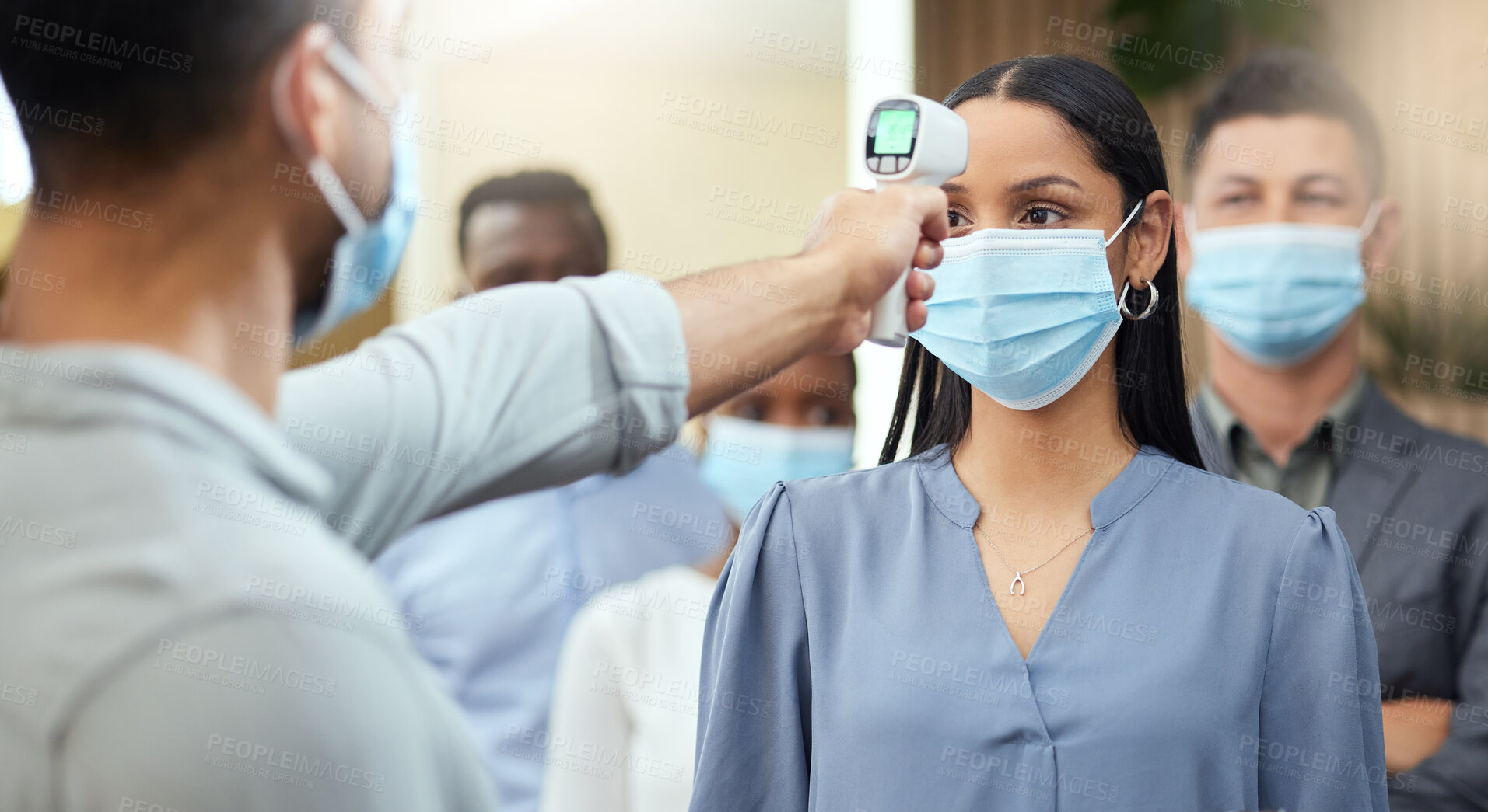 Buy stock photo Cropped shot of an attractive young businesswoman wearing a mask and having her temperature taken while standing at the head of a queue in her office