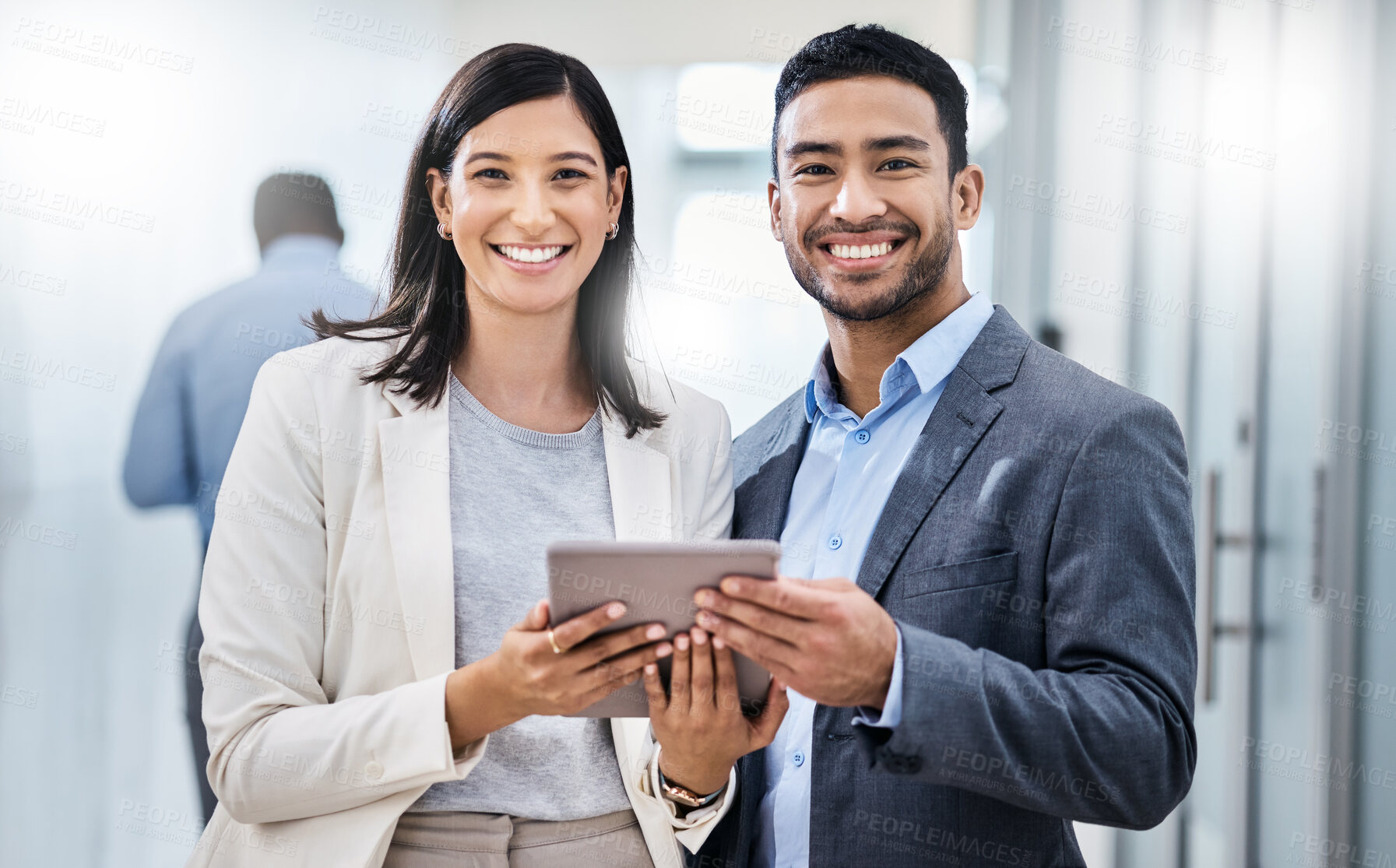 Buy stock photo Shot of two businesspeople standing together and holding a digital tablet in an office