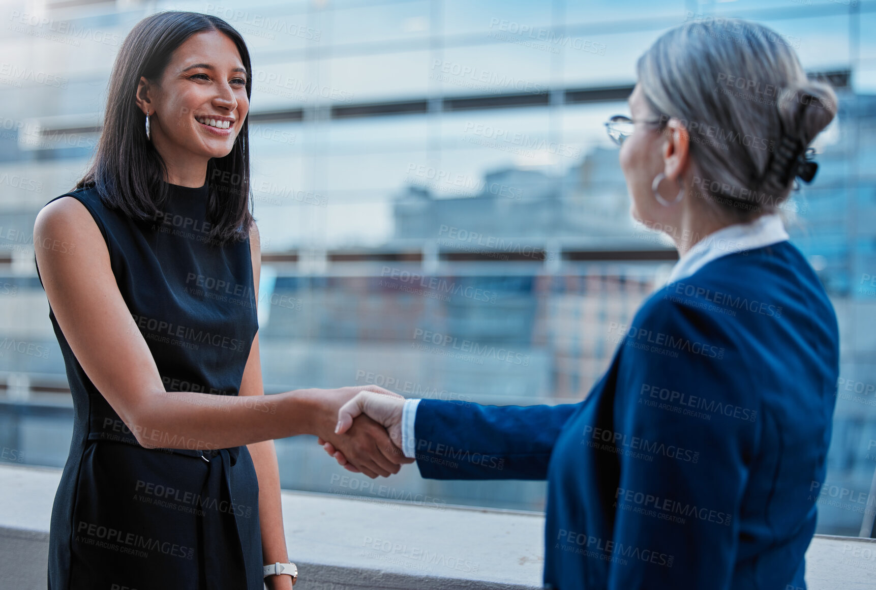 Buy stock photo Cropped shot of an attractive young businesswoman shaking hands with a mature female colleague outside on the balcony