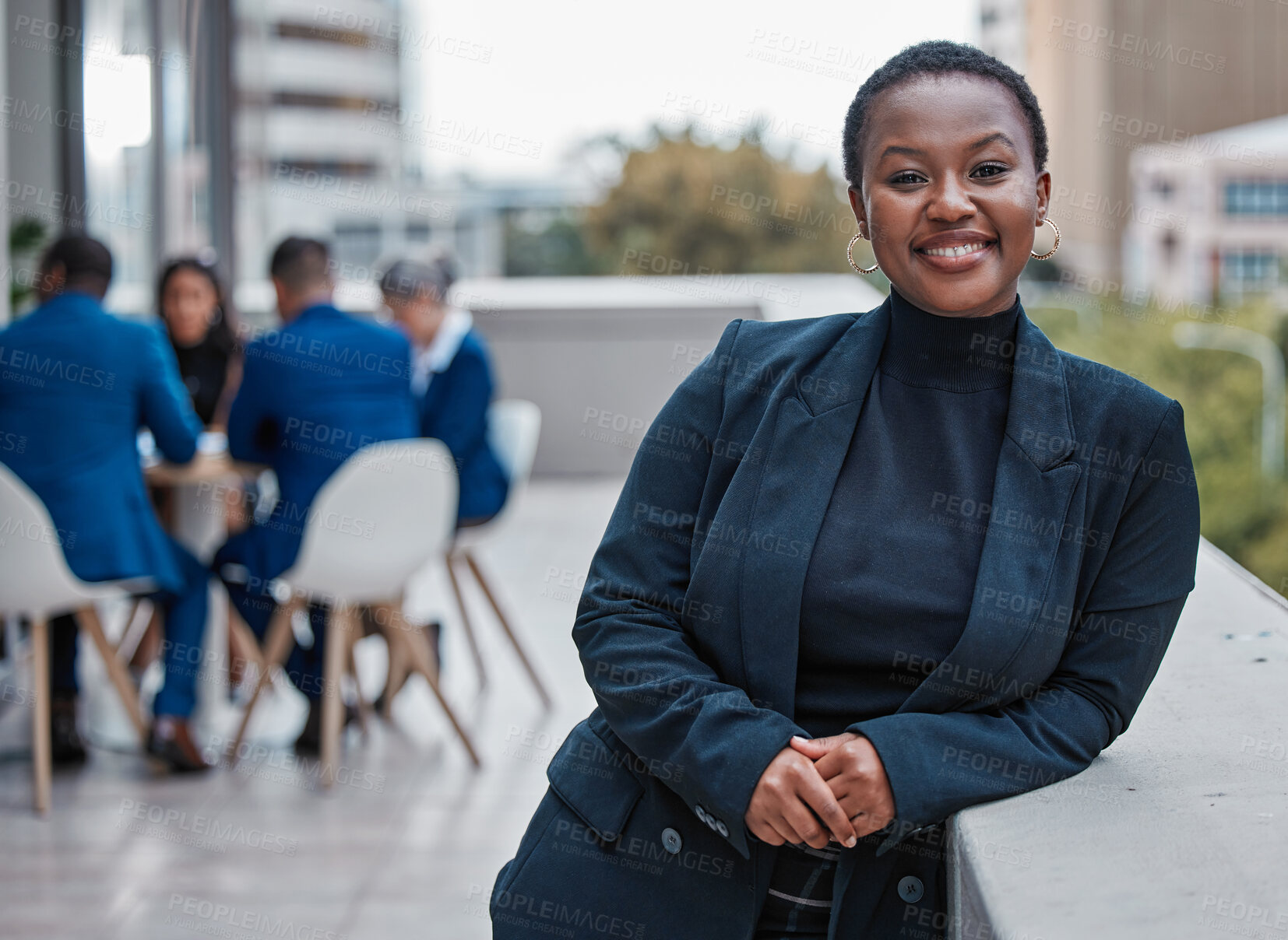 Buy stock photo Cropped portrait of an attractive young businesswoman standing outside on the office balcony with her colleagues in the background