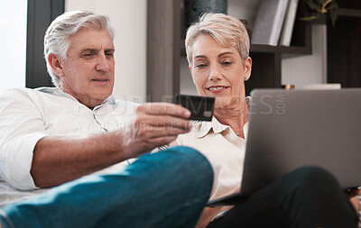 Buy stock photo Shot of a mature couple using a laptop and paying with a credit card at home together