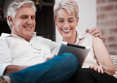 Buy stock photo Shot of a mature couple using a digital tablet at home on the sofa together