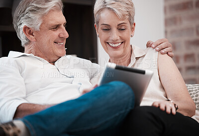 Buy stock photo Shot of a mature couple using a digital tablet at home on the sofa together