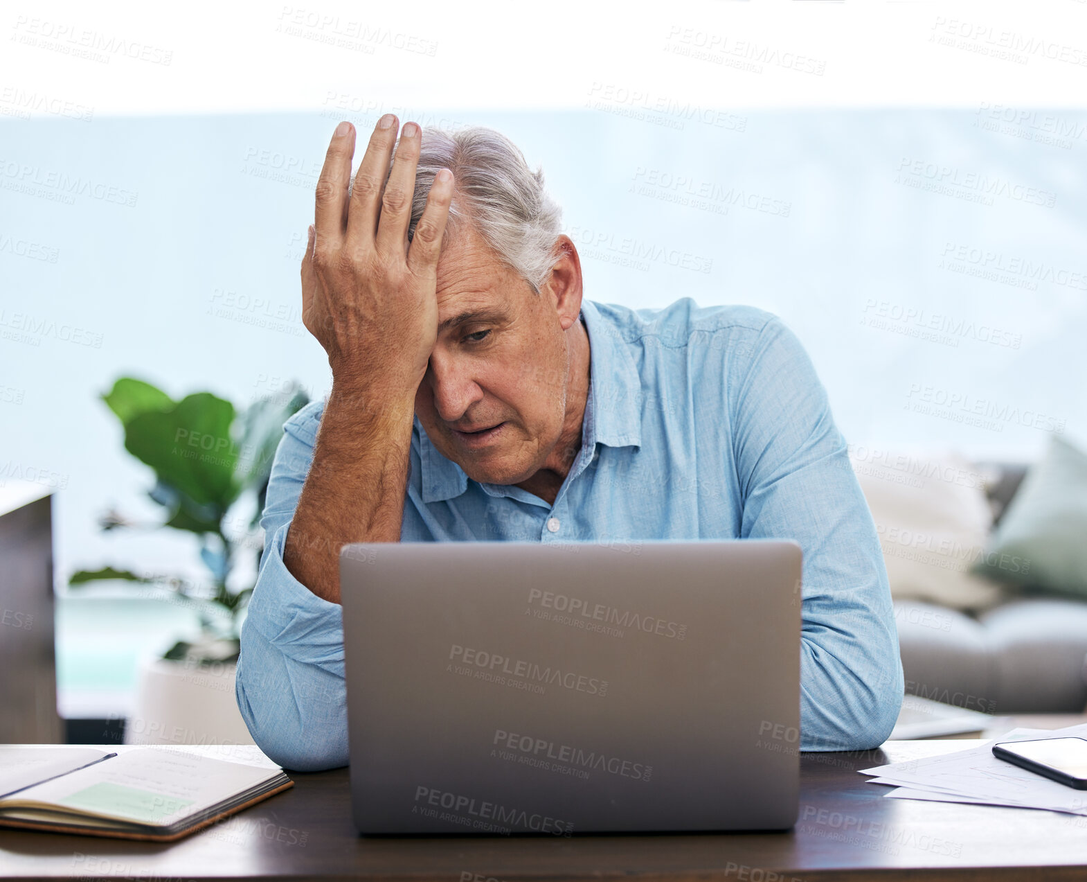 Buy stock photo Shot of a mature man sitting alone and feeling stressed while using his laptop to work from home