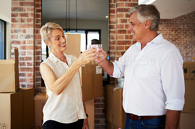 Buy stock photo Shot of a mature couple toasting with water after a successful day moving house