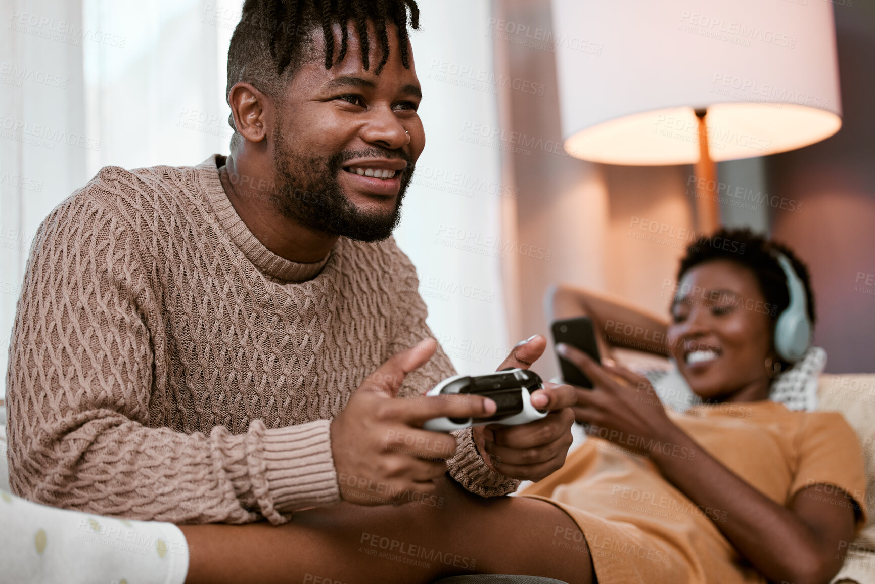 Buy stock photo Black couple, sofa and happy with entertainment for bonding, playing and streaming at home. Man, woman and together with relaxed on couch and phone for music, video games and fun in lounge in Nigeria