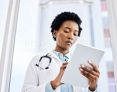 Buy stock photo Low angle shot of an attractive young female doctor using her tablet while standing in the office