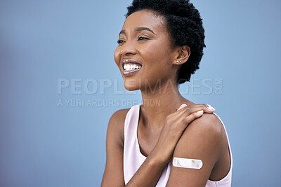 Buy stock photo Black woman, proud and vaccine plaster in studio for prevention, happy and booster shot on blue background. Medication, smile and female person with pride for promote wellness, healthcare or medicine