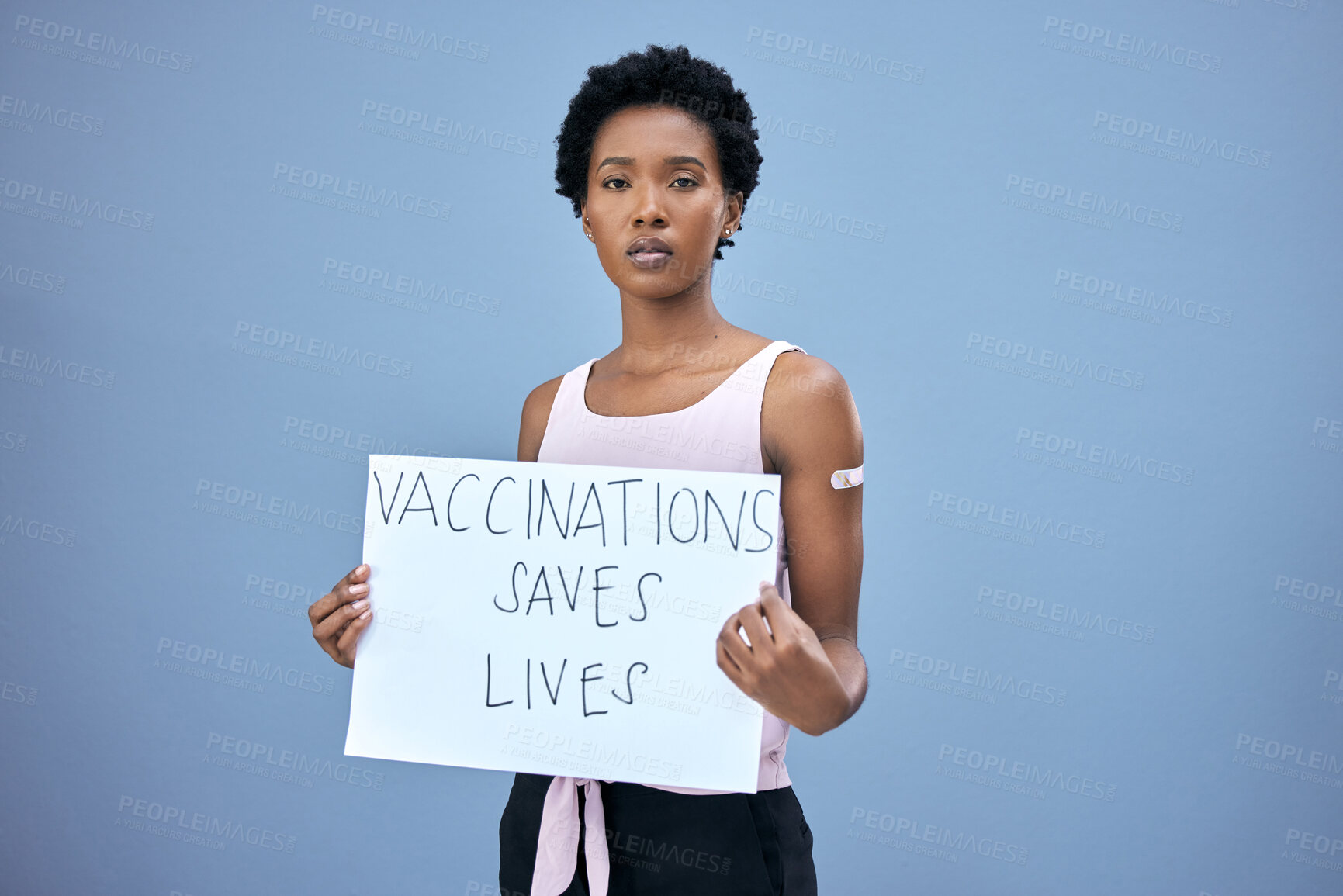 Buy stock photo Shot of an attractive young woman standing alone in the studio and holding a poster after getting her Covid vaccine