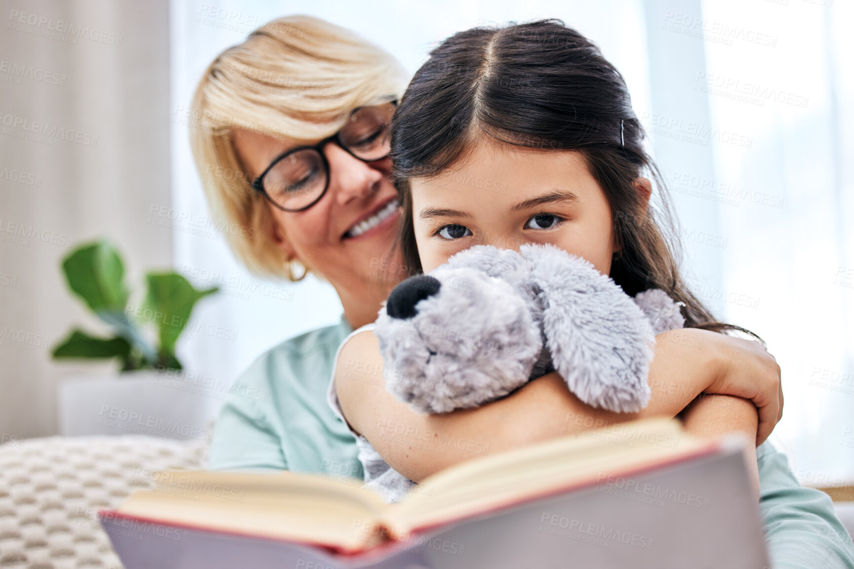 Buy stock photo Smile, book and senior woman with child reading for knowledge with teddy bear at home together. Happy, bonding and elderly grandmother relaxing and enjoying story with girl kid holding toy at house.