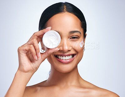 Buy stock photo Portrait of an attractive young woman applying moisturiser against a grey background
