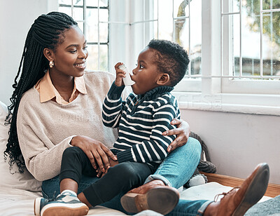 Buy stock photo Shot of a little boy using his inhaler while sitting at home with his mother