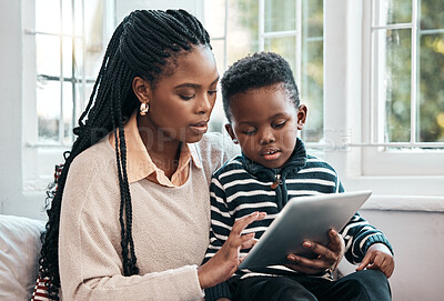 Buy stock photo Shot of a little boy and his mother looking at something on a digital tablet while sitting at home