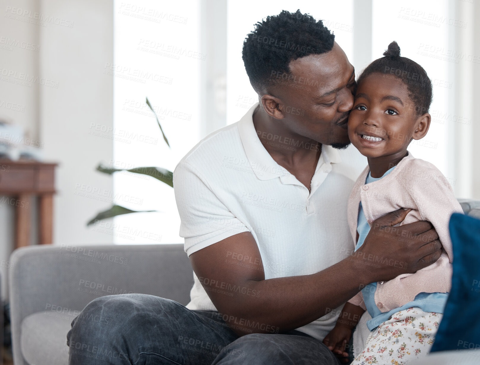 Buy stock photo Cropped shot of a handsome young man kissing his daughter on the cheek while relaxing in the living room at home