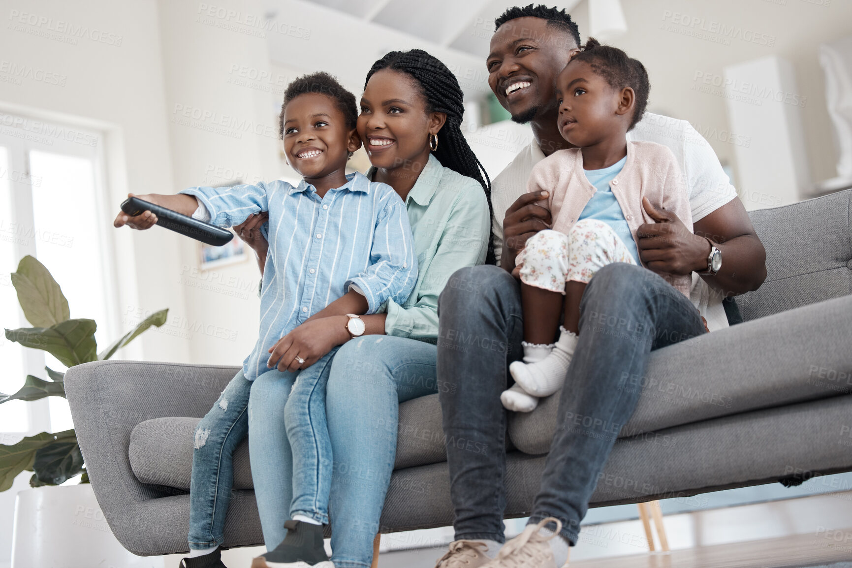 Buy stock photo Low angle shot of an affectionate young family of four watching TV in the living room at home