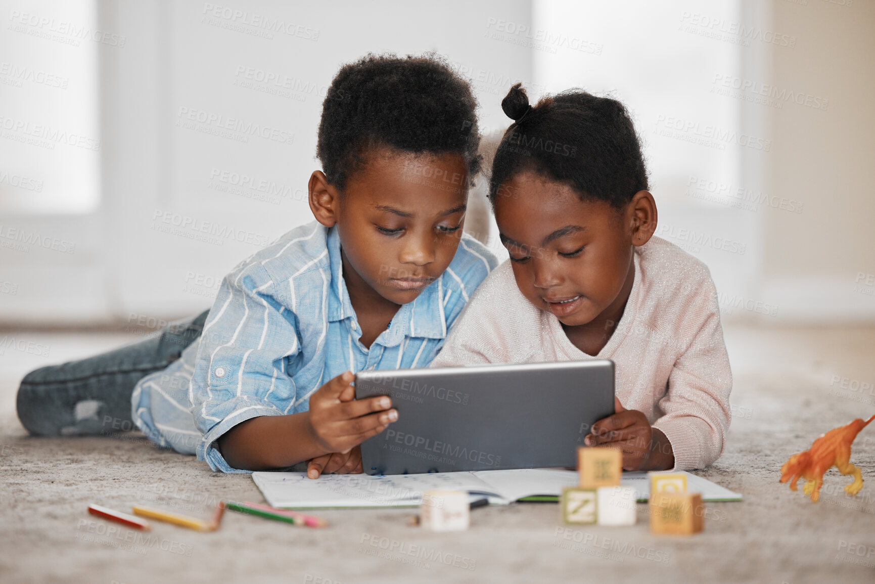 Buy stock photo Shot of a little boy and girl using a digital tablet together at home