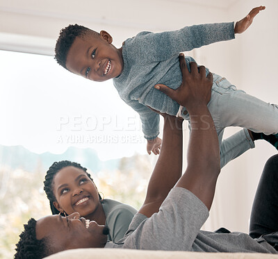 Buy stock photo Cropped portrait of an adorable little boy playing with his father on a bed at home while his mother watches on