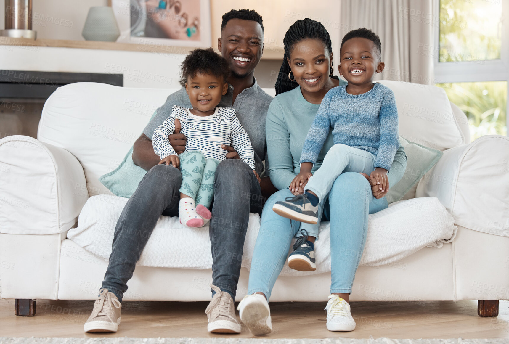 Buy stock photo Full length shot of a young couple sitting in the living room at home and bonding with their children