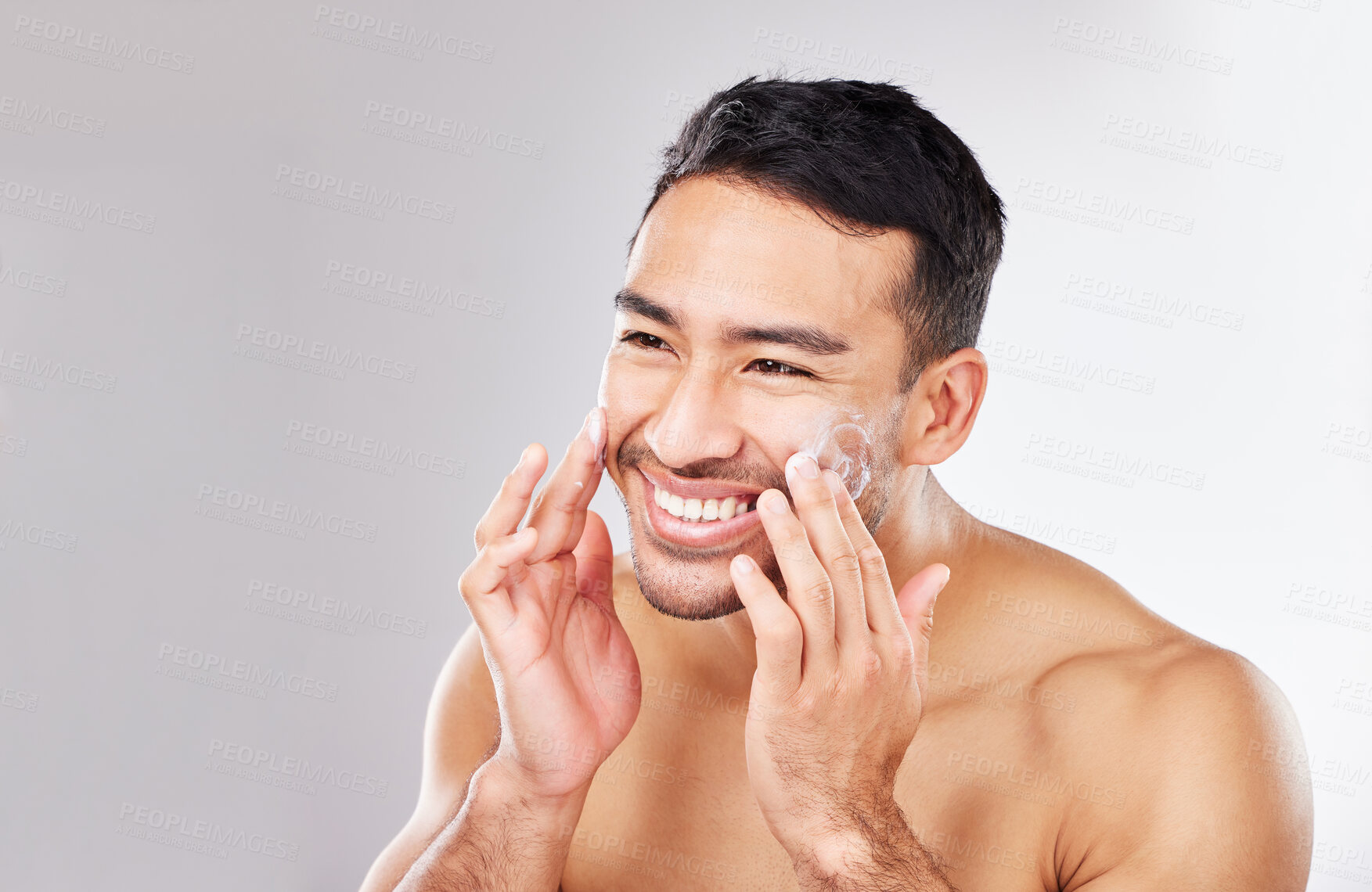 Buy stock photo Happy Asian man, face or cream for beauty in studio with smile, natural cosmetics or glow for shine. Dermatology, antiaging product or male model applying skincare lotion or creme on white background