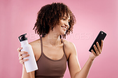 Buy stock photo Cropped shot of an attractive young female athlete checking her text messages in studio against a pink background