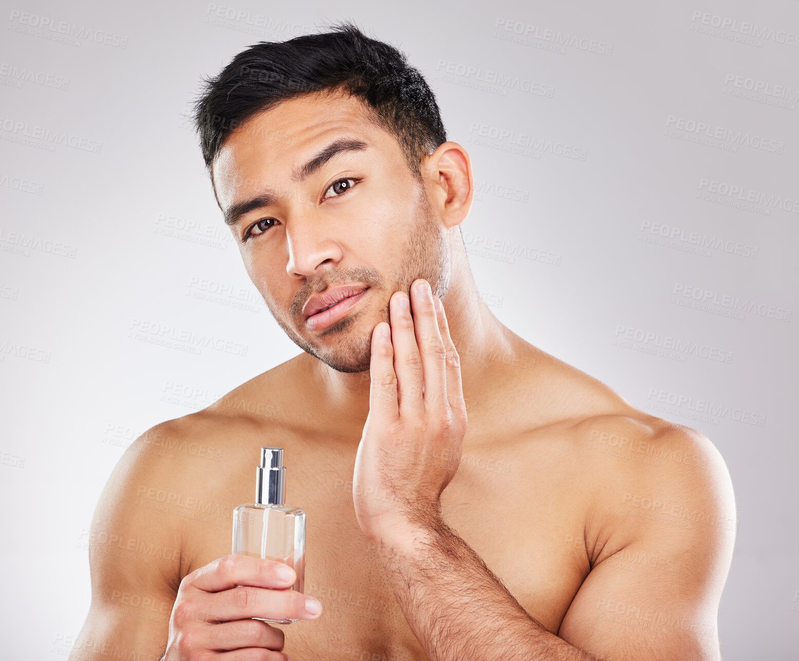 Buy stock photo Studio portrait of a handsome young man applying aftershave