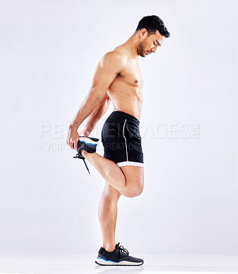 Buy stock photo Shot of a young man stretching his leg against a studio background