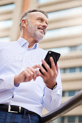 Buy stock photo Shot of a handsome mature businessman standing alone on the balcony outside and using his cellphone