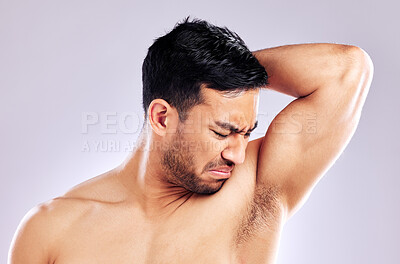 Buy stock photo Studio shot of a man frowning while smelling his armpit