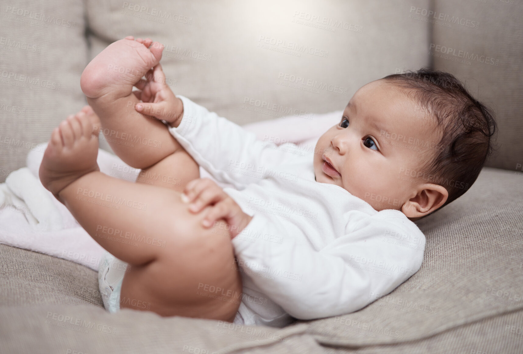 Buy stock photo Shot of an adorable baby lying on a couch at home