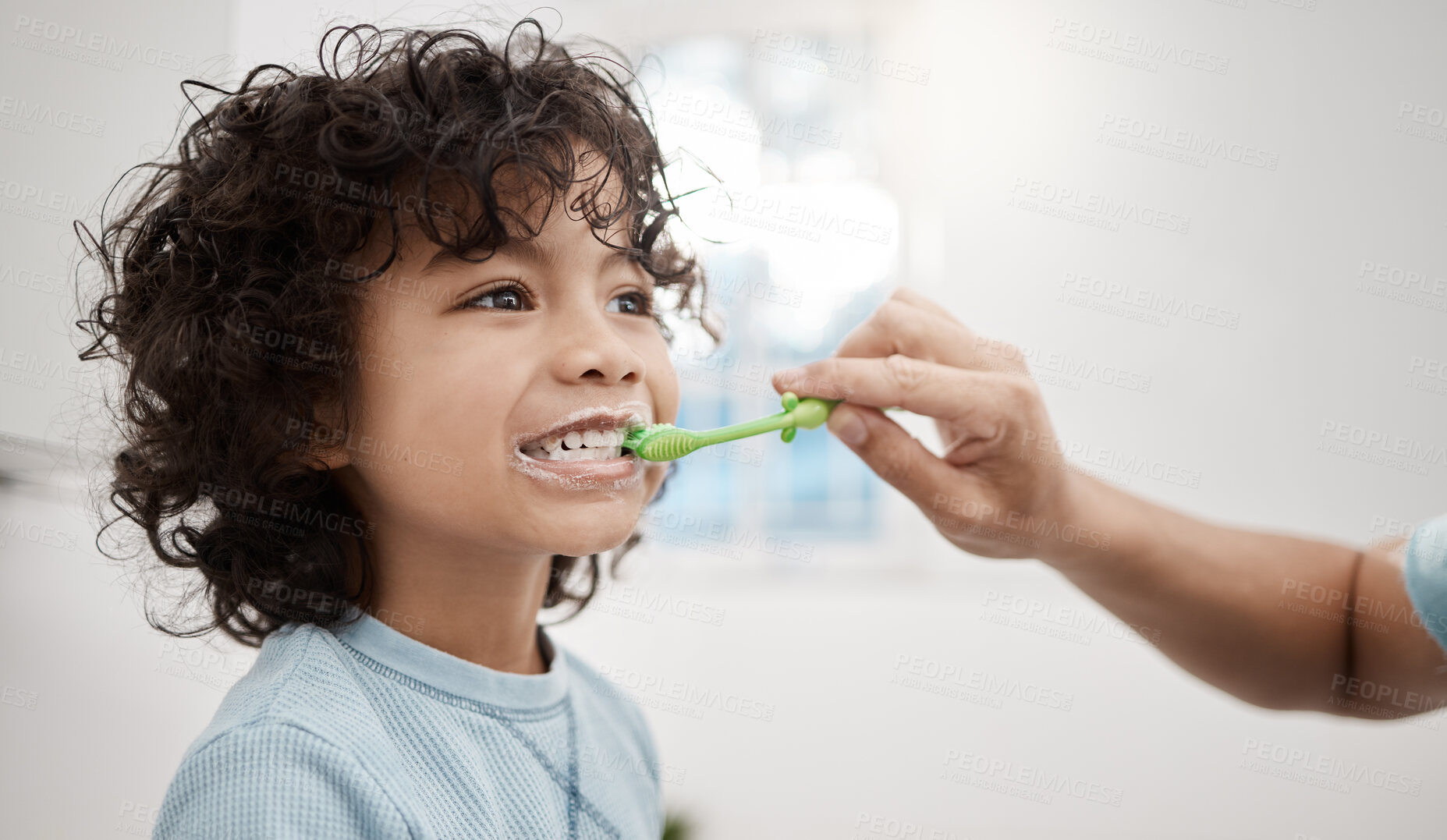 Buy stock photo Shot of a father brushing his little son's teeth in the bathroom at home