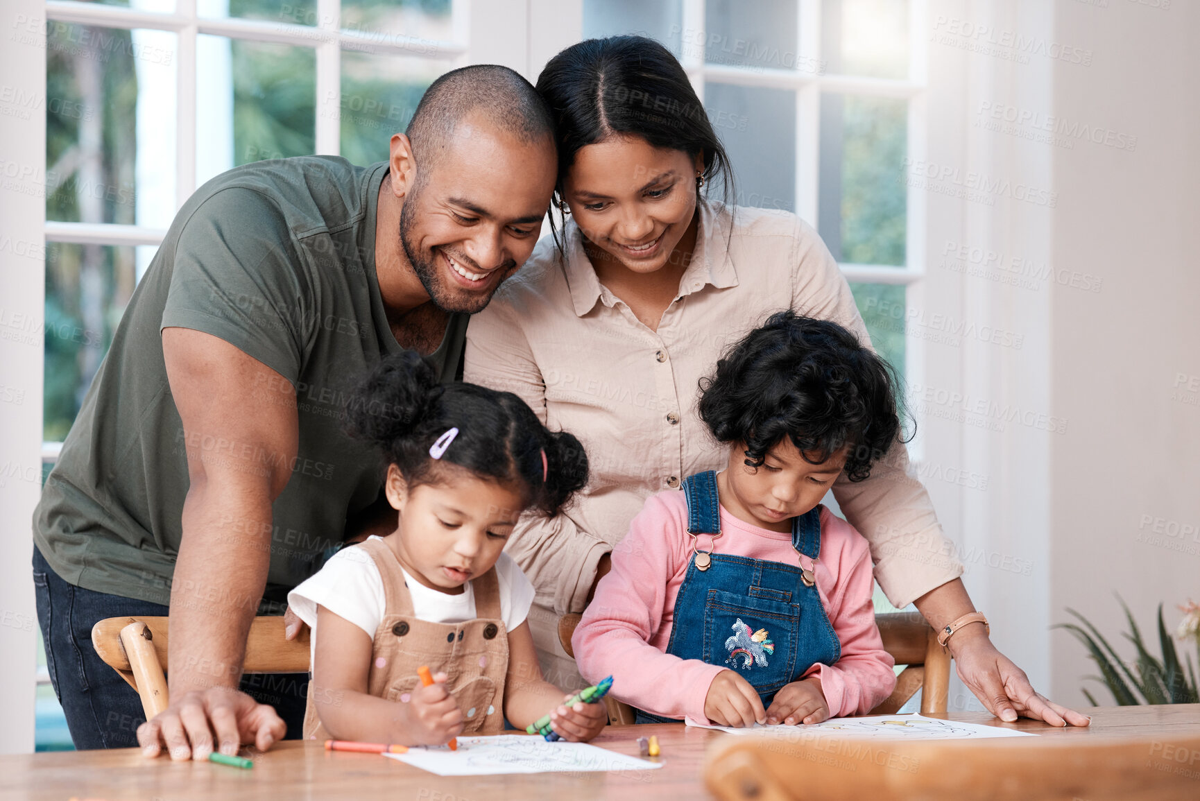 Buy stock photo Shot of a couple watching their two little daughters colouring with crayons at home