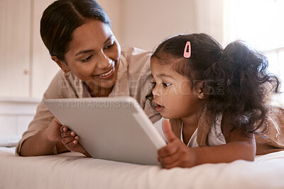 Buy stock photo Shot of a little girl using a digital tablet with her mother at home