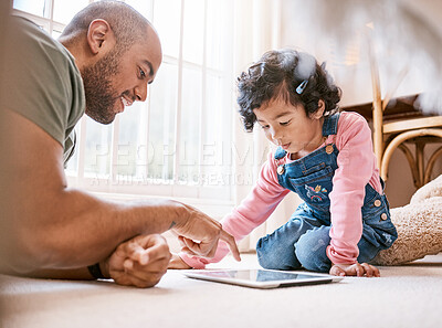 Buy stock photo Shot of a little girl using a digital tablet with her father at home