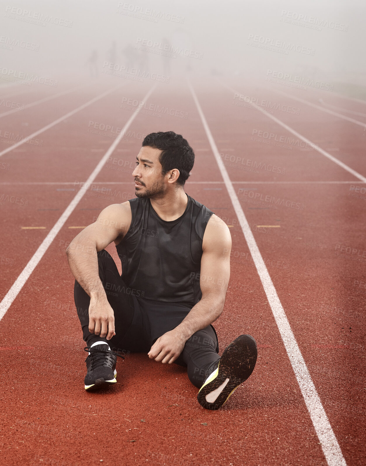 Buy stock photo Shot of a young male athlete sitting on the track before a race