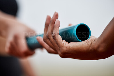 Buy stock photo Shot of two athletes passing a baton during a relay race
