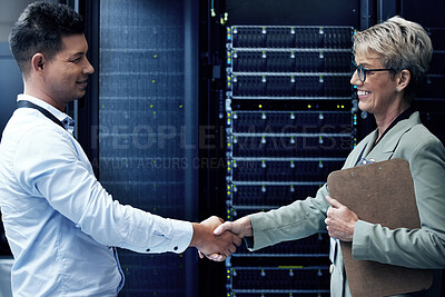 Buy stock photo Shot of two technicians shaking hands while working together in a server room