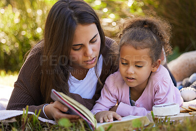 Buy stock photo Mother, child and reading book in nature, storytelling and bonding for love in childhood. Mama, daughter and relax on grass at outdoor picnic for literature, learning and fiction for education